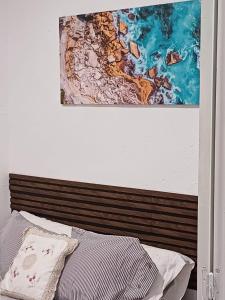 een bed met een houten hoofdeinde en een schilderij aan de muur bij Apartamento en el casco viejo de Castro Urdiales in Castro-Urdiales