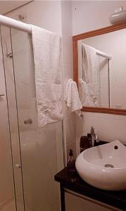 a bathroom with a white sink and a mirror at Apartamento compartilhado comigo mais 2 felinos in Foz do Iguaçu