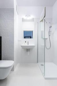 Baño blanco con aseo y lavamanos en UrbanNest_Krochmalna en Varsovia
