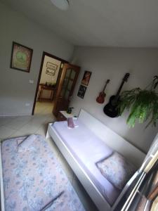 a room with a bed and guitars on the wall at Quarto Felicidade Cabeçudas in Itajaí