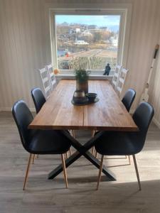 une table à manger avec des chaises et une grande fenêtre dans l'établissement Reinestua, à Moskenes