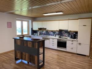 a large kitchen with white cabinets and a wooden table at Appealing apartment near lake in Argenbühl