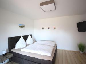 een slaapkamer met een bed met witte lakens en een televisie bij Bungalow Huus Seerose in Krummhörn