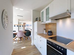 a kitchen with a clock on the wall and a table at Beach House Langeoog in Langeoog +22 photos