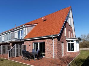 a brick house with a table and chairs on a patio at Beach House Langeoog in Langeoog