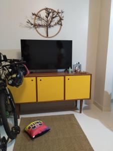 a yellow entertainment center with a flat screen tv at Quarto Praia do Frances in Marechal Deodoro