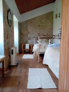 a bedroom with a bed and a stone wall at Casa do Loureiro in Ferrarias