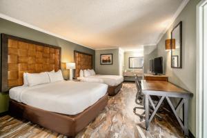 a hotel room with two beds and a desk and a television at The Buena Park Hotel & Suites in Buena Park