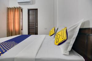 a bedroom with a bed with yellow and blue pillows at SPOT ON Ekam Guest House in Patiāla