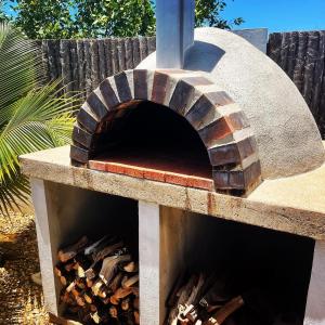 a stone pizza oven with a pile of wood at Royal Rat Hostel in Placencia