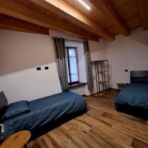 een slaapkamer met 2 bedden en een houten vloer bij La Maison de Joanna 3 in Châtillon