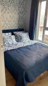 uma cama com um edredão azul ao lado de uma janela em Apartament Szarotki em Szczecin