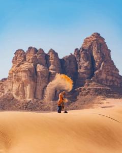 un hombre parado en el desierto con humo llegando en wadi rum fox road camp & jeep tour, en Wadi Rum