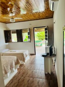 a bedroom with two beds and a television in it at Pousada e Restaurante Alto da Serra in Bonito