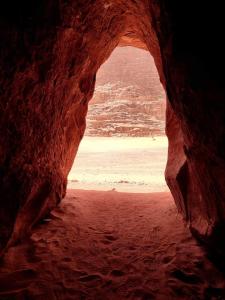a cave with a view of the beach through at wadi rum fox road camp & jeep tour in Wadi Rum