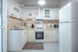 La cuisine blanche est équipée d'un évier et d'un réfrigérateur. dans l'établissement Cozy Athens Apartment, à Athènes