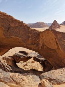an arch in the desert with mountains and rocks at wadi rum fox road camp & jeep tour in Wadi Rum