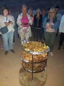 a group of people standing around a table of food at wadi rum fox road camp & jeep tour in Wadi Rum