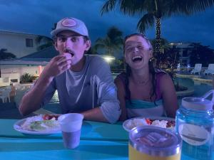 a man and a woman sitting at a table with food at Royal Rat Hostel in Placencia