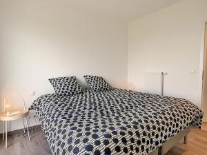 a bedroom with a bed with a black and white comforter at Magnifique appartement 2 chambres à Liège Ougrée in Seraing