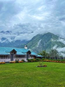 um edifício num campo com uma montanha ao fundo em Bharmour villa em Brāhmaur