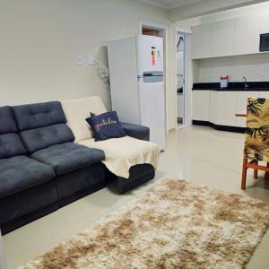 Una sala de estar con un sofá negro y una cocina. en Apartamento Veraneio em Bombinhas, en Bombinhas 18 fotos más