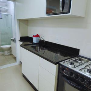 Una pequeña cocina con fregadero y estufa. en Apartamento Veraneio em Bombinhas, en Bombinhas