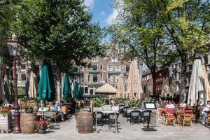 una calle de la ciudad con mesas, sillas y sombrillas en Vondelpark Luxury Apartment, en Ámsterdam
