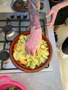 a person holding a bowl of vegetables on a stove at kasbah souss cooking in Agadir