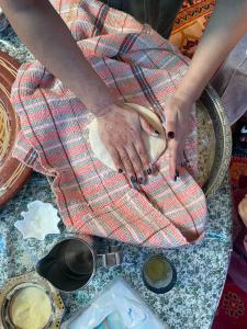 a person holding a piece of dough on a table at kasbah souss cooking in Agadir