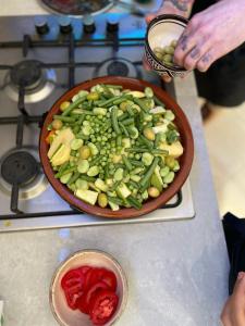 kasbah souss cooking في أغادير: وعاء من الخضروات على موقد مع وعاء من الطماطم