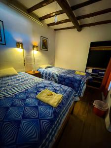 una camera con due letti con lenzuola blu e bianche di Casa Cusco guest house a Cuzco