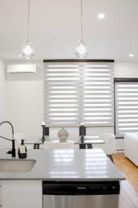 cocina con encimeras blancas, fregadero y 2 ventanas en Luxurious Modern Royalty in Plateau Mont-Royal - 3, en Montreal
