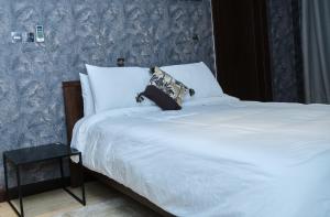 uma cama com lençóis brancos e almofadas num quarto em Apartment 8 em Acra