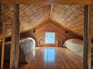 two beds in a log cabin with a window at Hilltop Villa at Lake Porontima in Kuusamo