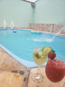 a drink and a strawberry in a glass next to a swimming pool at Casa de temporada in São João Batista do Glória