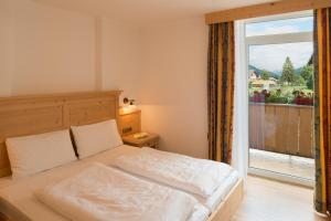 a bedroom with a bed and a large window at Apparthotel Germania in Dobbiaco