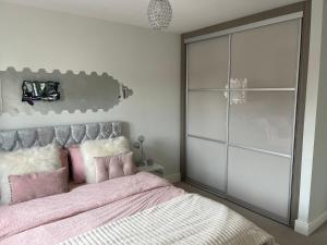ein Schlafzimmer mit einem großen rosa Bett mit rosa Kissen in der Unterkunft En-suite bedroom in a family home near Gatwick airport and Horley station in Hookwood
