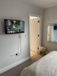 a bedroom with a bed and a flat screen tv on the wall at En-suite bedroom in a family home near Gatwick airport and Horley station in Hookwood