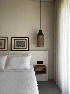 ein Schlafzimmer mit einem weißen Bett und einer Hängeleuchte in der Unterkunft On The Rocks Villas Ios in Chora, Ios