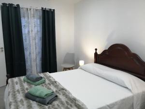 a bedroom with a bed with two towels on it at Casa do Roberto in Lajes das Flores