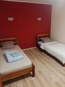 2 Betten in einem Zimmer mit roten Wänden und Holzböden in der Unterkunft Pariska Noć in Loznica