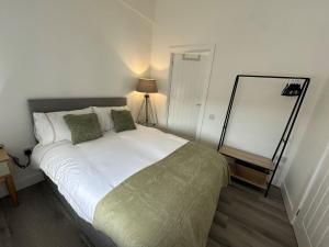 a bedroom with a large white bed with green pillows at Carmen Sylva Studio flat Llandudno sea front in Llandudno