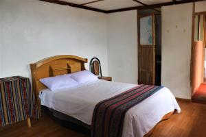 a bedroom with a large bed with a wooden headboard at INKA LAKE Taquile Lodge in Huillanopampa