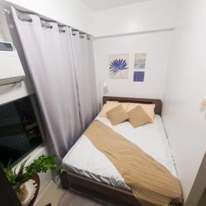 Studio For Rent in Upper Mckinley Hill, Taguig في مانيلا: غرفة نوم صغيرة مع سرير مع ملاءات ووسائد بيضاء