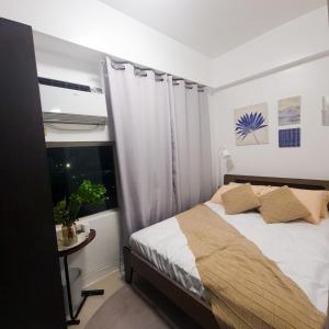 Studio For Rent in Upper Mckinley Hill, Taguig في مانيلا: غرفة نوم بسرير ونافذة