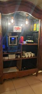 a kitchen with a microwave and a shelf with dishes at H&ocirc;tel de Bretagne Dol centre ville in Dol-de-Bretagne