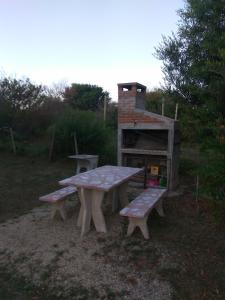 una mesa de picnic y dos bancos en un campo en Brisa de Mar., en La Pedrera