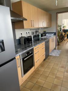 uma cozinha com armários de madeira e electrodomésticos de aço inoxidável em La Petite Malouine em Dunkerque