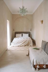 a bedroom with two beds and a chandelier at Riad Le Sable Vert in Marrakech